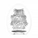 A white, egg-shaped Tenga Egg Standard 3 Pack Disposable Masturbators II encases a modern abstract vase with horizontal and diagonal slats for an intricate open-weave design, set against a plain white background.