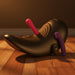The Cowgirl Saddle Sex Machine with Vibration, Thrusting, and Rocking—featuring a black curved seat with pink and purple silicone dildos—rests on a wooden floor in warm light, offering hands-free pleasure and self-rocking motion.