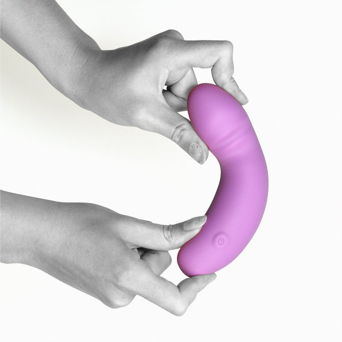 A pair of hands holding The Glee Spot Ultra Soft First Time Flexible Silicone Vibrator in purple by Creative Conceptions, showcasing its smooth surface and a textured section near the top. This waterproof G-spot vibrator features a button at the base, hinting at its electronic nature as a personal massager or vibrator, all set against a plain white background.