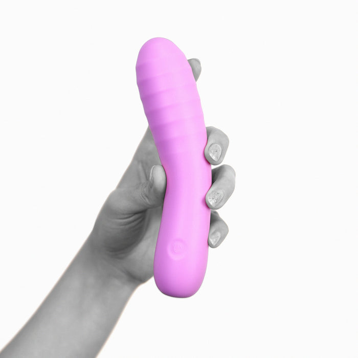 A hand holding a purple, curved Glee Spot Ultra Soft First Time Flexible Silicone Vibrator by Creative Conceptions, made of silky silicone with a ribbed texture at the top. The background is white, making the waterproof vibrator the focus of the image.