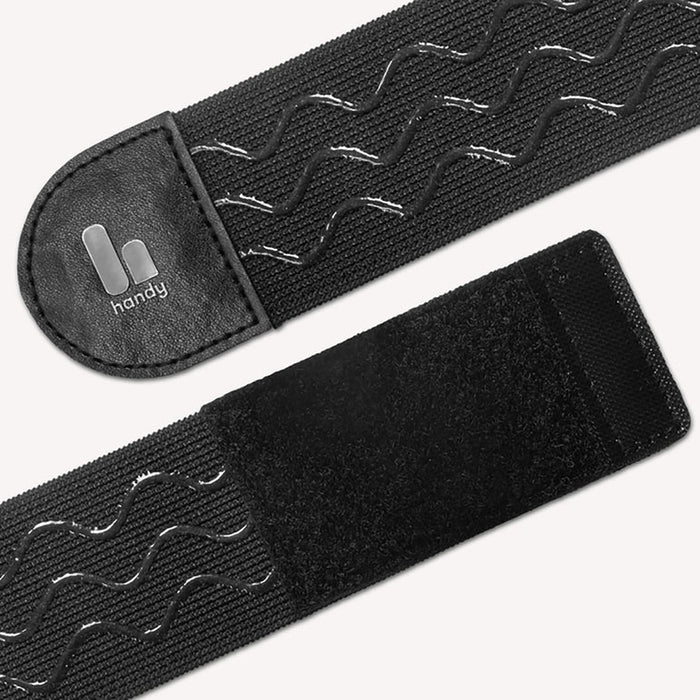 Close-up of The Handy TrueGrip Pro Band, a black elastic sleeve holder with wavy anti-slip silicone grip lines, Velcro ends, and a small “handy” logo on a leather-like patch.