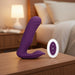 A purple, curved silicone vibrator with a textured design, known as The Velvet Hammer Thrusting Hands-Free Dual Stimulation Vibrator by Evolved Novelties, is shown next to a white, oval-shaped remote control with four buttons: a "+" symbol, a "-" symbol, a power button, and a waveform button. This waterproof vibrator ensures versatile pleasure for any moment.