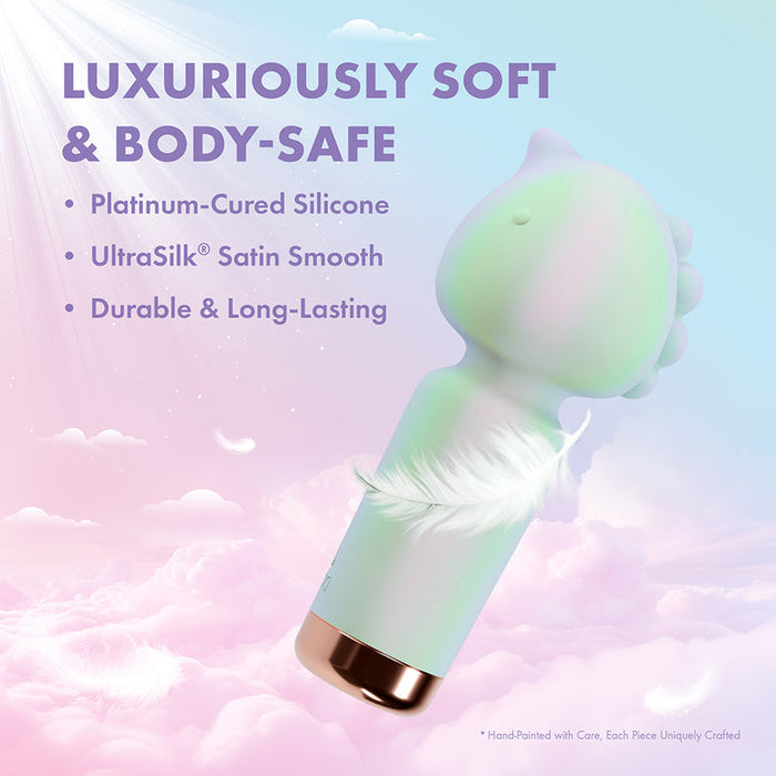 A pastel dinosaur-shaped vibrator made of platinum-cured, UltraSilk satin-smooth, luxuriously soft body-safe silicone rests on a dreamy background. Meet the Unicorn Dreams Mini Wand – Magical Pleasure Awaits.