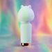 The Unicorn Dreams Mini Wand – Magical Pleasure Awaits, a small white bear-shaped vibrator with a rose gold base, stands upright against a pastel rainbow background. Made of body-safe silicone, it features a smooth, minimalist design with subtle facial details.
