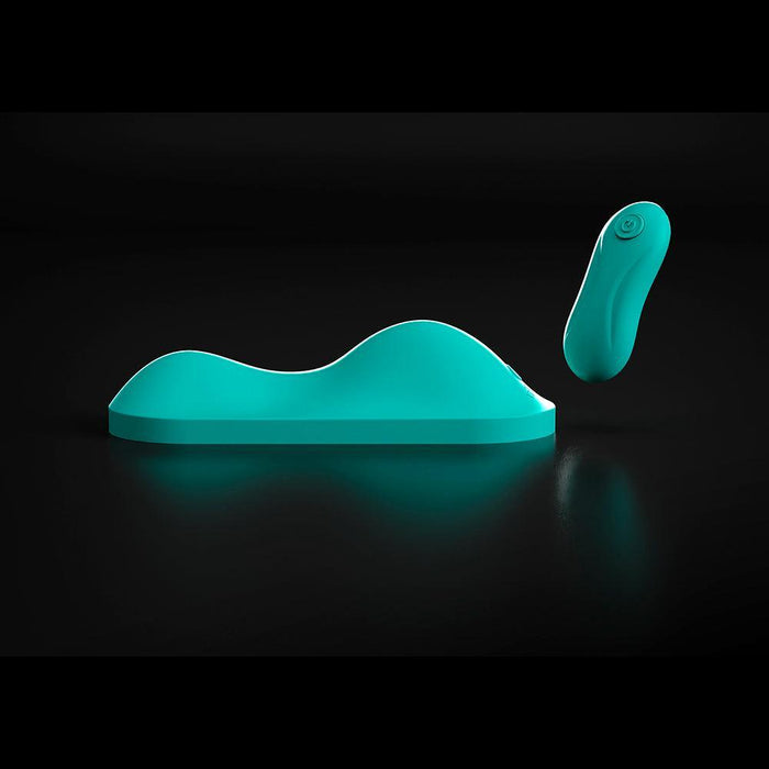 The VibePad Intense Ultra Powerful Ride On Hands-Free Humping Vibrator, a teal wave-shaped waterproof toy with a matching wireless remote and sleek modern design, is displayed on a black background.