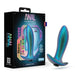 The image showcases a shimmering, metallic blue anal plug placed beside its box. The packaging is labeled "Anal Adventures Matrix" and prominently features product information and branding from Blush, highlighting it as the Voyager Smooth Vibrating Butt Plug & Prostate Massager made of silicone for an adventurous experience.
