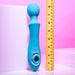 The Evolved Novelties Wanderful Sucker Double Ended Wand + Clitoral Pulsation Vibrator in electric blue is displayed standing beside a yellow ruler for size reference. The ruler shows that the silicone massager measures approximately 10 inches long. The backdrop features a gradient of soft pink and white tones.