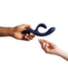 A hand with dark skin is passing a blue We-Vibe Nova 2 Powerful Flexible G-Spot Rabbit Vibrator to a hand with light skin. Both hands are photographed against a white background.