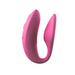The We-Vibe Sync Remote and App Controlled Wearable Couples Vibrator in Dusty Pink by We-Vibe is a U-shaped vibrator featuring textured inner surfaces and a sleek exterior design.