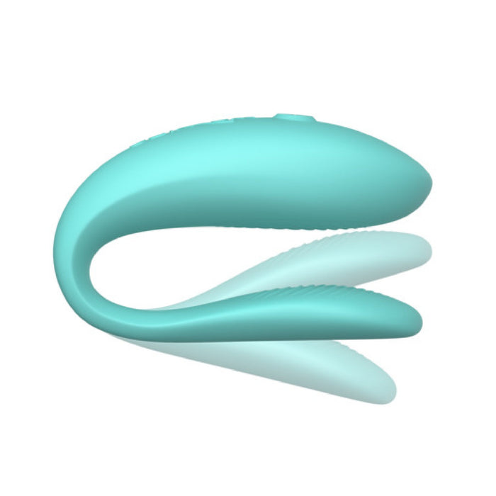 An aqua-colored, ergonomic, curved device with a sleek design. The image showcases the We-Vibe Sync Lite App Controlled Wearable Couples Vibrator by We-Vibe, featuring a dual-arm structure for flexible use against a plain white background.