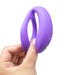 A hand holding the We-Vibe Sync O Hands-Free Wearable Couples Vibrator in purple, a sleek U-shaped silicone device featuring a small button. This product from We-Vibe has a smooth texture and is clearly designed for personal use. Its app control feature makes it perfect for tech-savvy users seeking convenience and functionality.