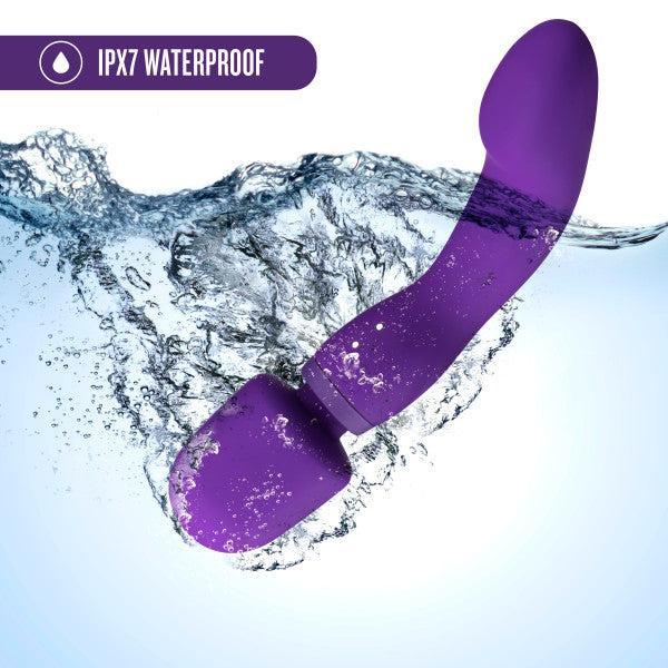Image of the Wellness Dual Sense Double Ended Ergonomic Waterproof Wand by Blush being submerged in water with a splash. The text "IPX7 Waterproof" is displayed in the upper left corner next to a water droplet icon. The background features light blue water and air bubbles illustrating underwater use, emphasizing its dual sense capabilities.