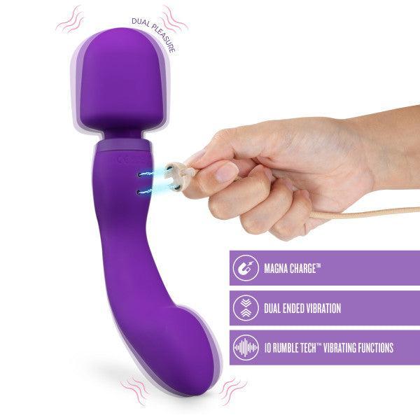A purple Wellness Dual Sense Double Ended Ergonomic Waterproof Wand by Blush being charged with a magnetic charger. It features a curved design with a large, round head on one end. The image highlights features like "Magna Charge," "Dual Ended Vibration," "10 Rumble Tech Vibrating Functions," and it's also a waterproof sex toy.