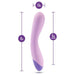 Introducing the Wellness G Curve Rumbly Waterproof Silicone G-Spot Vibrator by Blush—a lavender-colored vibrator specially designed with a slight curve. Crafted from silky silicone, it measures 8 inches in total length, with a 6-inch insertable length and a diameter of 1.5 inches at its widest point. Perfect for G-spot exploration, its base is adorned in a darker purple shade.

