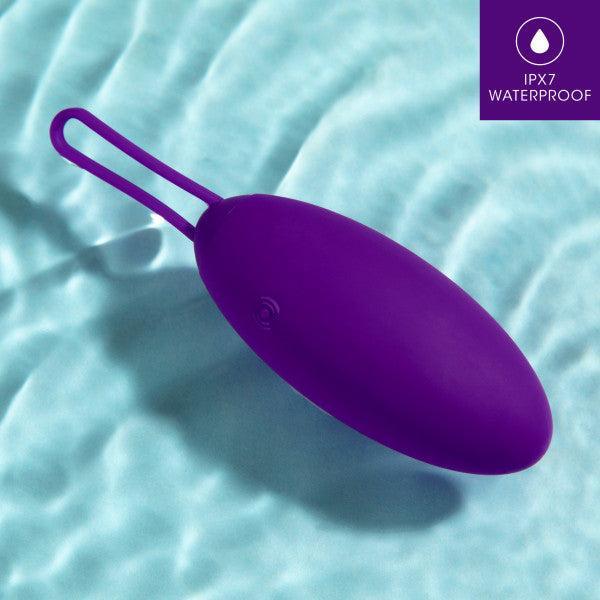The "Blush Wellness Imara Wearable Vibrating Egg with Remote - Purple," an oval-shaped waterproof device with a loop handle, is floating on a light blue water surface. Made of ultra silky silicone, the image features a label in the top right corner indicating "IPX7 Waterproof".