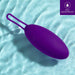The "Blush Wellness Imara Wearable Vibrating Egg with Remote - Purple," an oval-shaped waterproof device with a loop handle, is floating on a light blue water surface. Made of ultra silky silicone, the image features a label in the top right corner indicating "IPX7 Waterproof".
