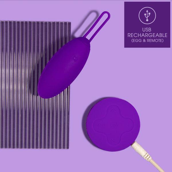 A Wellness Imara Wearable Vibrating Egg with Remote – Purple from Blush is placed on a purple background. Made from ultra silky silicone, this USB rechargeable device comes with a wireless remote control in the same rich hue. The top right corner of the image features a "USB Rechargeable (egg & remote)" label.