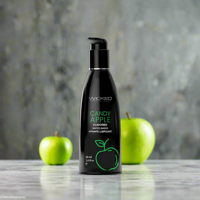 A black bottle of Wicked Lubes' Wicked Aqua Candy Apple Flavored Water Based Lubricant, featuring a 2 fl. oz. capacity, minimalist green apple graphics, and a convenient pump dispenser at the top.