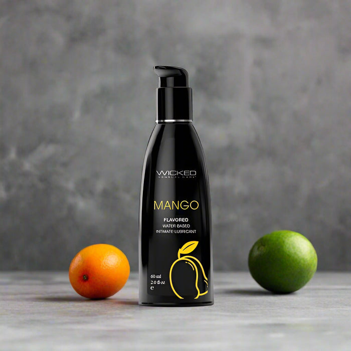 A black bottle of Wicked Lubes' Wicked Aqua Mango Flavored Water Based Lubricant, featuring a black pump top with yellow text and an image of a mango on the front. The bottle contains 60 ml (2.0 fl oz) of long-lasting mango lubricant.