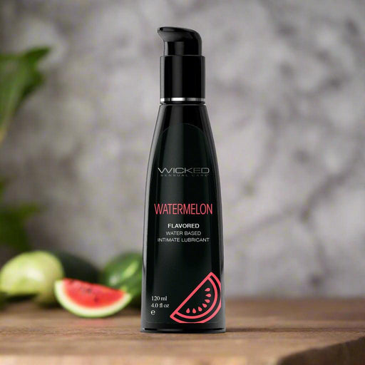 A sleek black bottle of Wicked Lubes' paraben-free, Wicked Aqua Watermelon Flavored Water Based Lubricant with a convenient pump dispenser. The 120 ml (4 fl oz) bottle features a charming pink watermelon slice graphic on the lower right side and is sex toy friendly.
