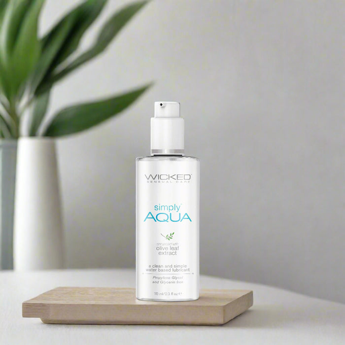 A sleek, 2.3 fl oz travel-size bottle of Wicked Lubes' "Simply Aqua" water-based lubricant, enriched with olive leaf extract. The design features a white pump dispenser and blue text, highlighting its vegan and cruelty-free formula.