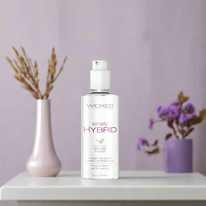Introducing the Wicked Simply Hybrid Lubricant 2.3 oz by Wicked Lubes, featuring a sleek white and silver design with olive leaf extract and a convenient pump dispenser. This clean and simple creamy hybrid lubricant is long-lasting, vegan, and formulated without propylene glycol and glycerine.
