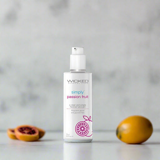 A bottle labeled "Wicked Simply Passion Fruit Flavored Water Based Lubricant 2 oz" from Wicked Lubes stands upright against a plain white background. It features a pump dispenser, purple graphics including a passion fruit illustration, and promotes itself as a glycerin-free, paraben-free water-based lube with a pH balanced formula.