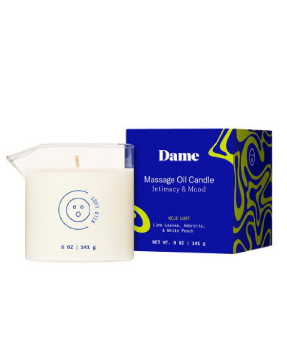 A glass jar labeled "Wild Lust Massage Oil Candle by Dame (Lime Leaf, Ambrette & White Peach)" sits beside its blue and yellow box, which highlights plant-based massage oil for intimacy and mood.
