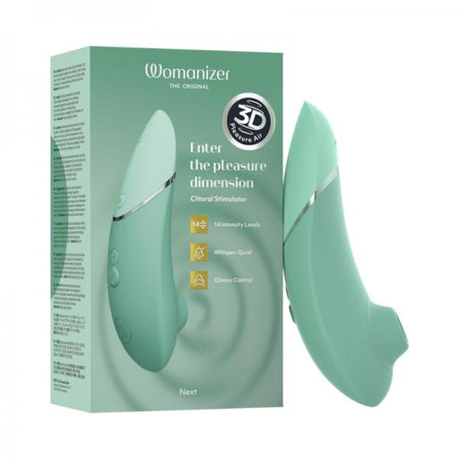 Image of a sage green Womanizer Next Pleasure Air Clitoral Vibrator standing upright next to its box. The box is also sage green, with text highlighting features like "14 Intensity Levels," "Whisper-Quiet," and "Enter the pleasure dimension." Experience the revolutionary Pleasure Air Technology for ultimate climax control.