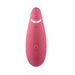 A sleek, raspberry-colored, oval-shaped electronic device with multiple buttons on its surface, including a power button, a wave symbol, plus and minus signs, and a circular logo at the bottom. The Womanizer Premium 2 Pleasure Air Clitoral Stimulator by Womanizer features innovative Pleasure Air technology for an unparalleled experience.