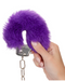 Ultra Fluffy Furry Cuffs - Purple being held by a hand close up on a white background