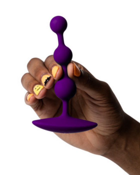 Romp Amp Flexible Anal Beads being held by a hand on a white background