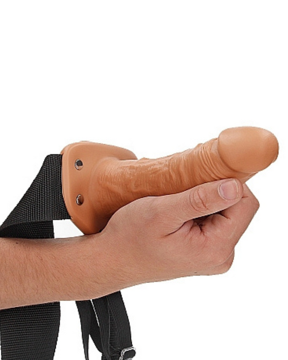 Caramel Realrock 6 Inch Hollow Dildo & Strap-on Harness being held by a hand on a white background
