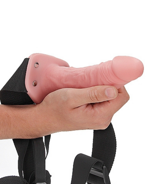 Vanilla Realrock 6 Inch Hollow Dildo & Strap-on Harness  being held by a hand on a white background