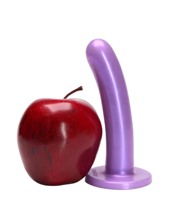 An apple and a Tantus Bend Over Intermediate 2 Dildos + Vibrating Strap-on Harness - Purple standing side by side on a white background.