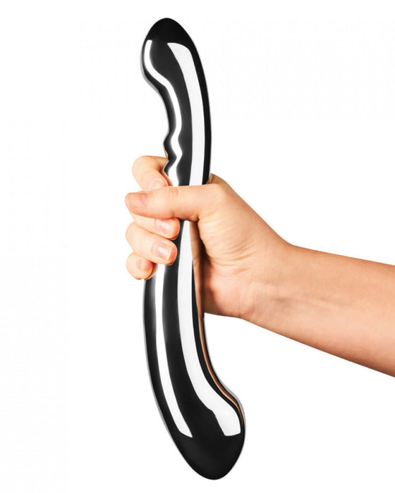 Le Wand Contour Double Ended Stainless Steel Dildo held at the center by a person's hand to illustrate the size of the dildo
