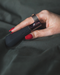 Hot Octopuss Digit Silicone Rechargeable Finger Vibrator worn by a woman with long nails and red nail polish against black silk sheets