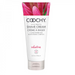 A tube of Classic Brands Coochy Oh So Smooth Shave Cream - Seduction with conditioner and moisturizing complex, suitable for sensitive skin, in a 'seduction' fragrance, against a background of vibrant flower petals.