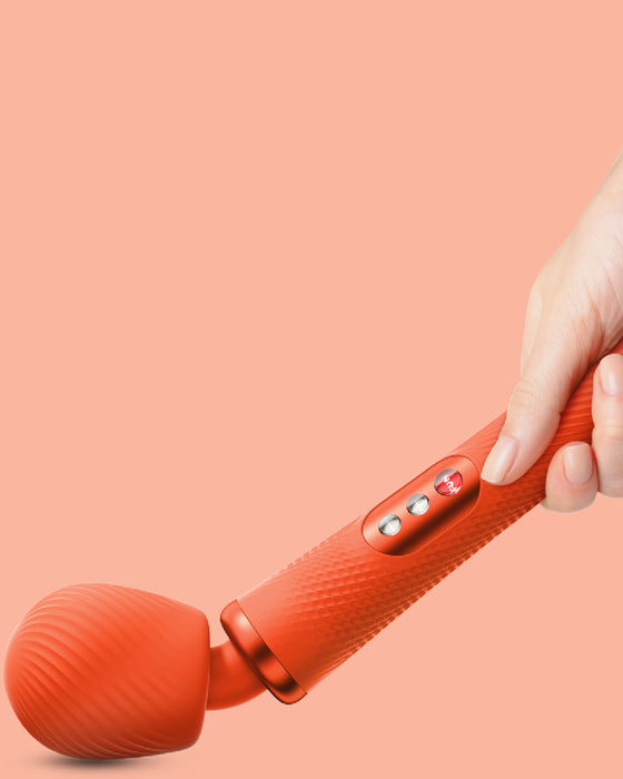 Fun Factory Vim Flexible Wand Vibrator - Orange  with bent neck held by hand on peach background 