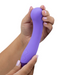 A hand holding a purple, body safe silicone Wellness G Ball Silicone G-Spot Vibrator with Rolling Tip with a curved design against a white background. (Blush)