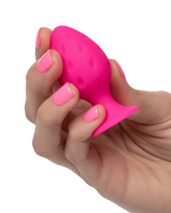 Cheeky Probe: 2 Graduated Textured Silicone Anal Plugs - Pink with smaller plug held in a woman's hand against a white background
