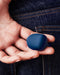 Dame Fin Rechargeable Silicone Finger Vibrator  navy held between a person's two first fingers palm out, behind a denim clad bum