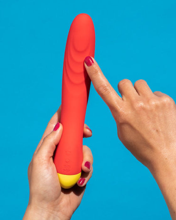 A hand showcasing a waterproof WOW Hype Beginner's Silicone G-Spot Vibrator against a blue background.