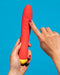 A hand showcasing a waterproof WOW Hype Beginner's Silicone G-Spot Vibrator against a blue background.