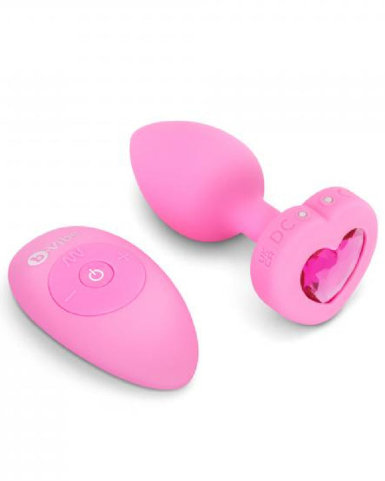 B-vibe Vibrating Heart Shaped Jewel Anal Plug S/M - Pink next to remote 