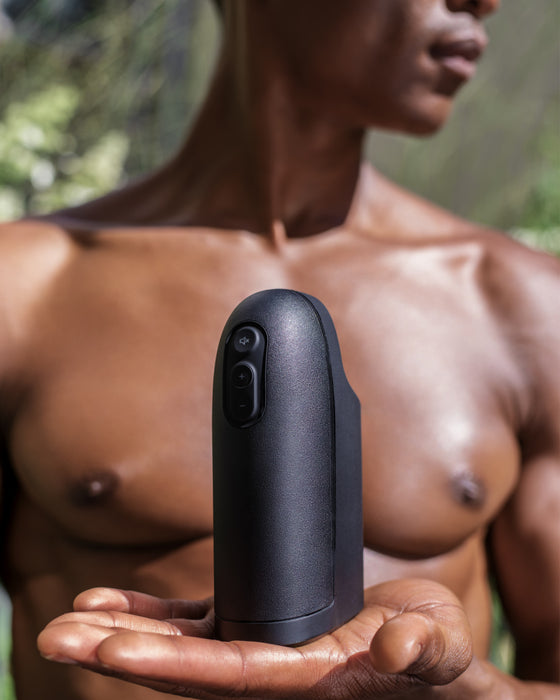 Arcwave Ion Pleasure Air Penis Masturbator held in a man's palm in front of his naked chest