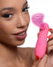 A confident woman holding a pink Shegasm Travel Sidekick Clitoral Suction Stimulator by XR Brands, showcasing the product with a bright smile.