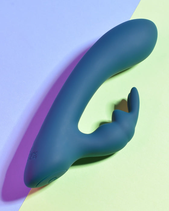 Playboy Little Rabbit Silicone Vibrator laying on green and purple background 