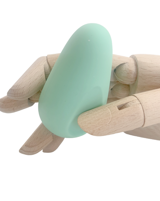 A wooden mannequin hand cradling a Ritual Chi Palm Sized Ergonomic Soft Silicone Bullet Vibrator by Doc Johnson against a white background.