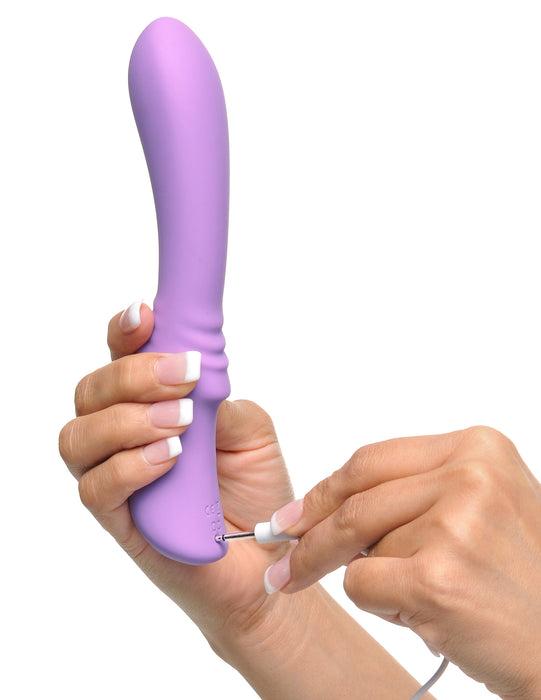 Fantasy For Her Flexible Please-Her Silicone Vibrator held in a person's hand while they plug in the recharger